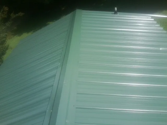 New green metal panels meeting at the ridge of a roof — Flat Roof Repair work by our crew in Dolomite