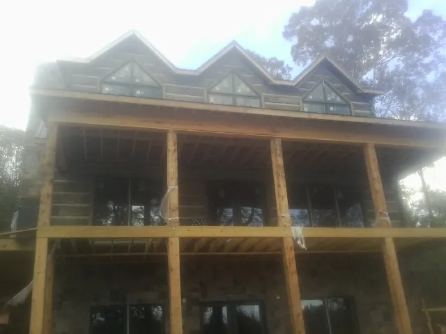 Dormers and porch framing on a large log home under construction — Roof Coating work by our crew in Dolomite