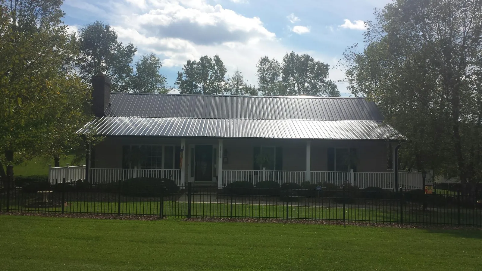 Gray metal roof on a brick ranch with a full width front porch — Gutter Guard Installation work by our crew in Dolomite