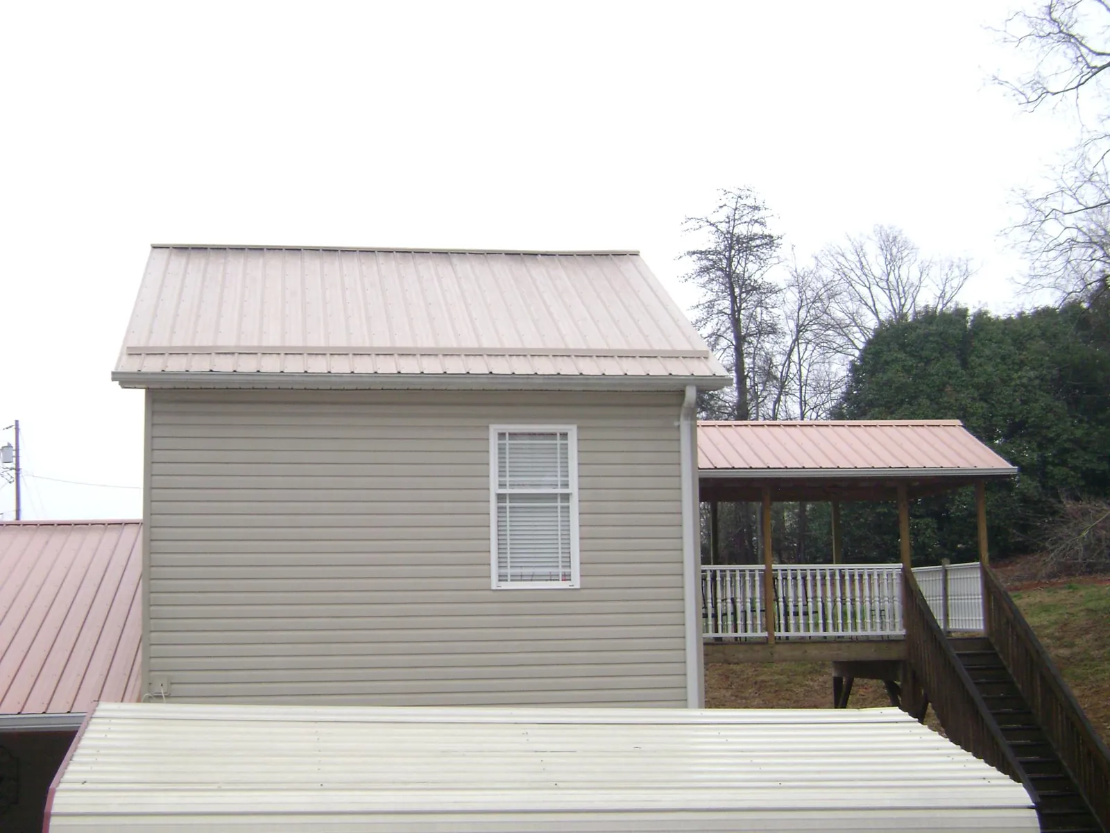 Tan metal roofs on a two story addition and attached porch, from a Roof Replacement job in Dolomite