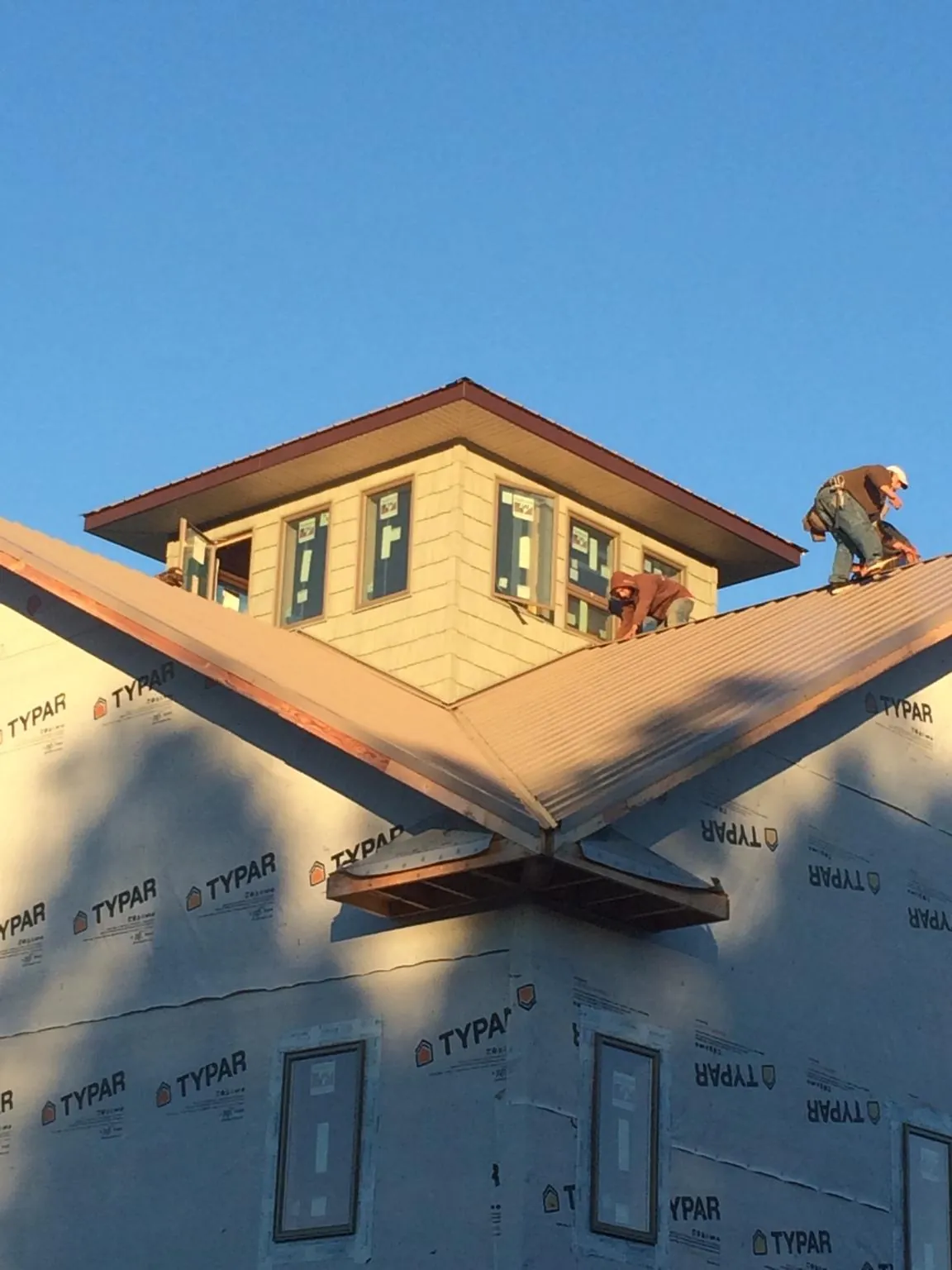Roofers working around a rooftop cupola on a new metal roof at sunset — Roof Waterproofing in Dolomite by Roofing Brothers